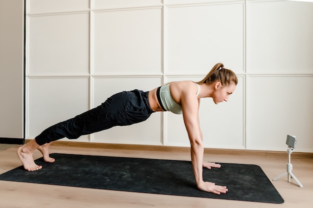 Atlética mulher fazendo exercício físico em casa no tapete de ioga
