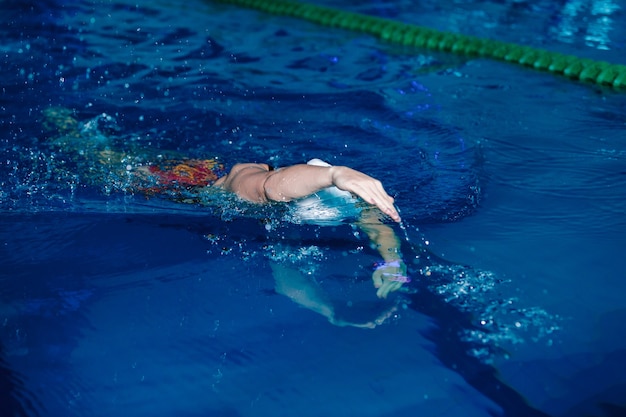 Atlética mulher nadando com boné e óculos na piscina