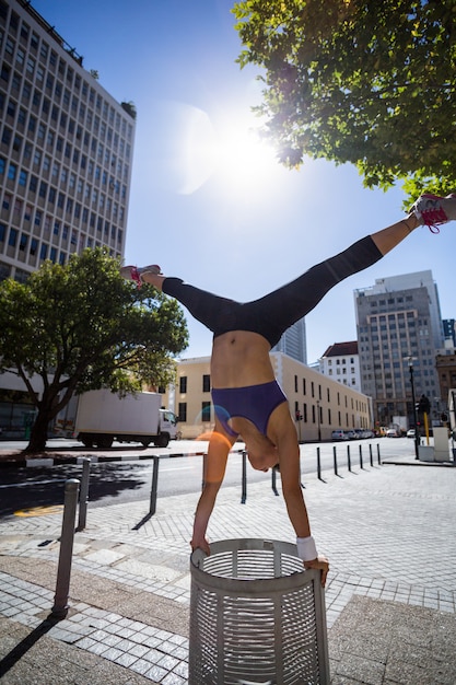 Atlética mulher realizando handstand e fazendo dividir na caixa