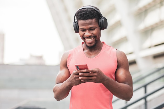 Atlético afro-americano ouve música em fones de ouvido e sorri no verão