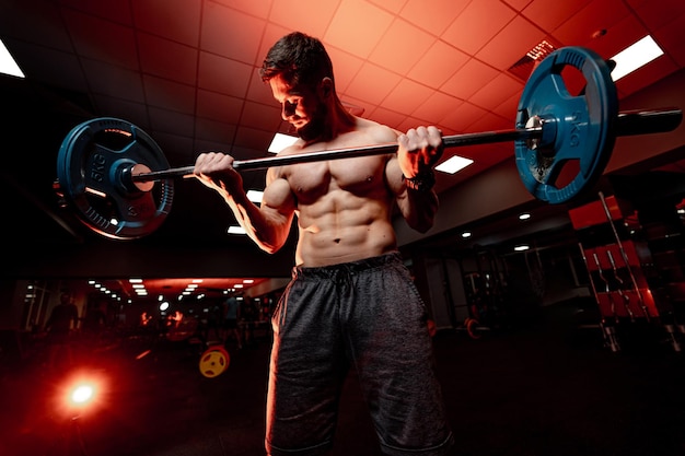 Atlético culturista sin camisa Muscular joven entrenando en el gimnasio