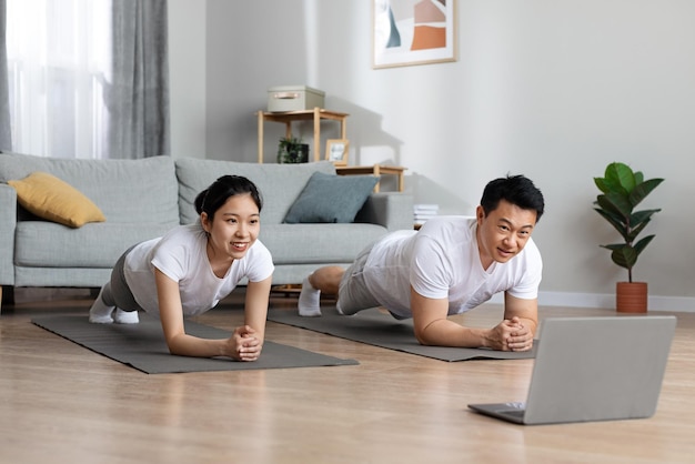 Atlético hombre y mujer asiáticos entrenando en casa usando un cuaderno