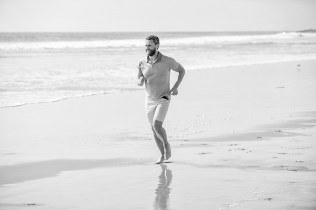 Atlético homem correndo na praia de verão para treinamento de verão