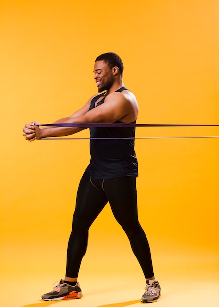 Foto atlético homem em roupa de ginástica, exercitando com banda de resistência