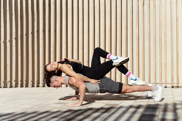 Atlético homem fazendo exercícios físicos com mulher nas costas na rua da cidade