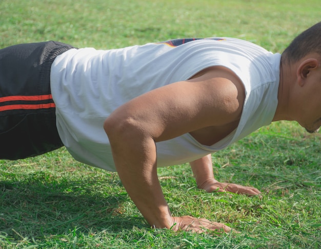 Atlético homem fazendo flexões no campo de grama para exercício