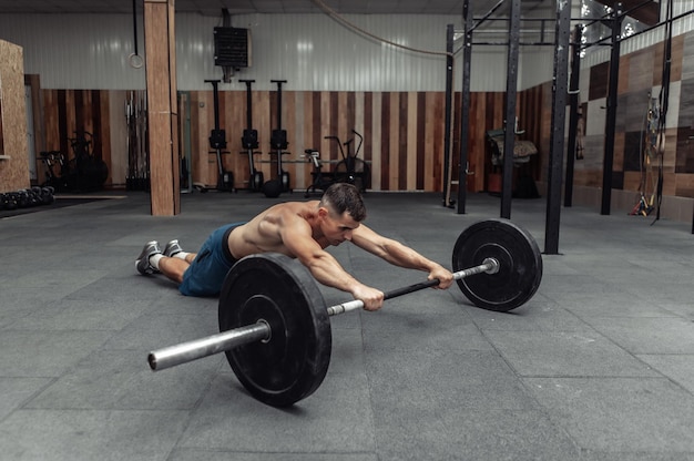 Atlético homem musculoso exercitando com barra no clube de saúde moderno. Musculação e Fitness