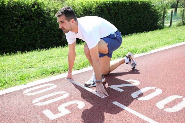 Atlético homem na pista começando a correr