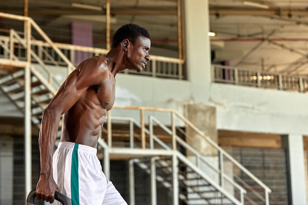 Atlético joven negro levantando un peso pesado en el gimnasio al aire libre bajo el puente Concepto de estilo de vida saludable