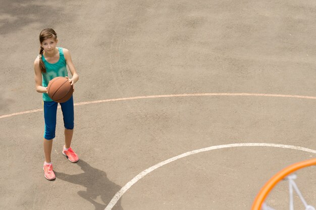 Atlético magro e bela jovem jogadora de basquete em pé com a bola