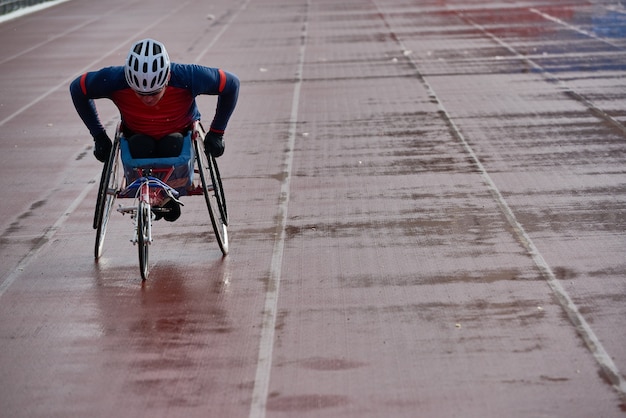 Foto atletismo en silla de ruedas. velocidad de entrenamiento de atleta masculino con discapacidad física de voluntad fuerte en silla de carreras en el estadio de pista y campo al aire libre