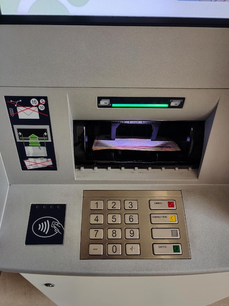 ATM-Display mit Zahlentasten und offener Banknotenausgabeeinheit mit Papiergeld in der Nähe