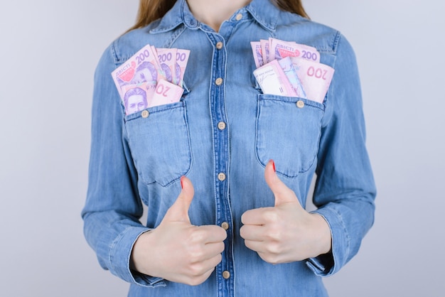 Atm lidar pilha jeans pessoa pessoas ok economia estudante diversão piada conceito engraçado. Foto recortada de close-up de animada alegre confiante senhora inteligente fazendo polegares para cima muito dinheiro, bolsos isolados de fundo