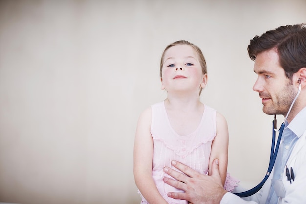 Atmen Sie tief ein Ein junger männlicher Arzt führt eine medizinische Untersuchung an einem kleinen Mädchen durch