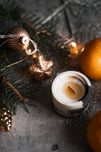 Atmósfera de Año Nuevo, una vela rodeada de ramas de abeto, mandarinas y árbol de Navidad