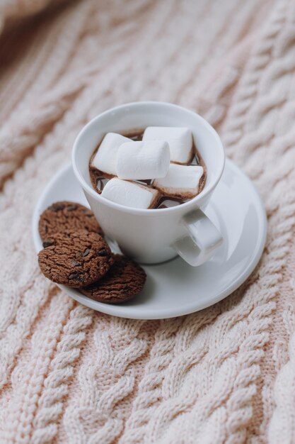 Atmosfera de casa de férias de inverno Bebida de cacau com marshmallows e biscoitos em suor de tricô rosa suave