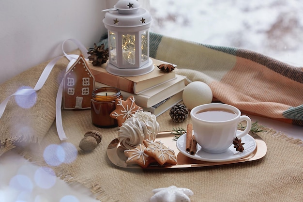 Atmosfera de inverno aconchegante Janela de Natal estética com livros biscoitos de gengibre nozes marshmallow xícara de café vela fundo aconchegante