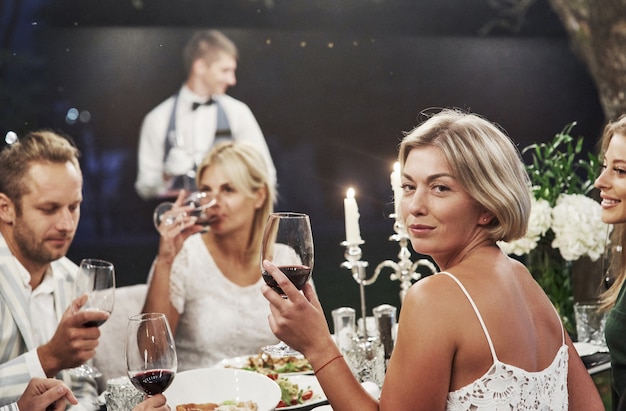 Atmósfera elegante. Grupo de amigos adultos descansan y conversan en el patio trasero del restaurante por la noche.