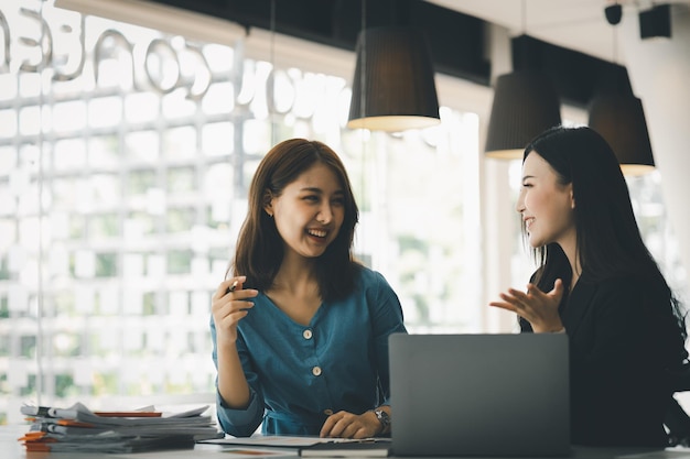 Atmósfera en la oficina de una empresa nueva, dos empleadas están discutiendo ideas para trabajar en resúmenes y planes de marketing para aumentar las ventas y preparar informes para los gerentes