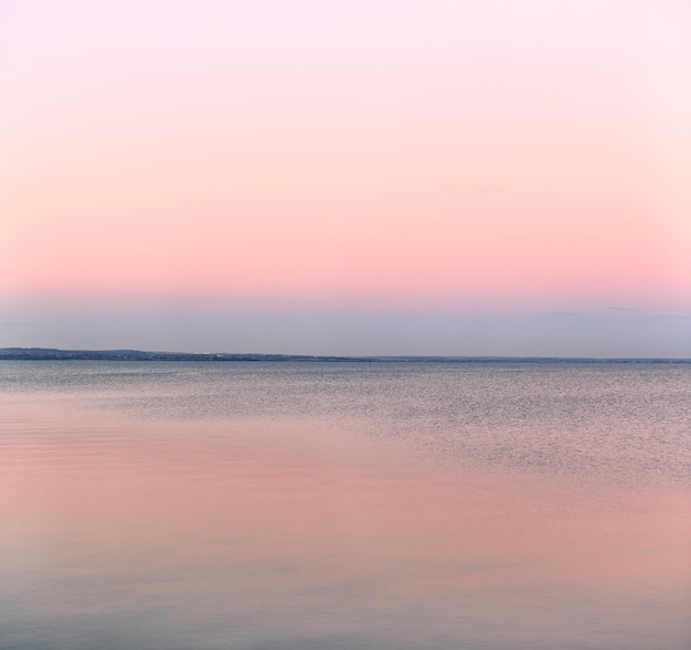 Atmosférico romántico rosa mar rojo puesta de sol cielo azul agua tranquila minimalista pacífico paisaje marino