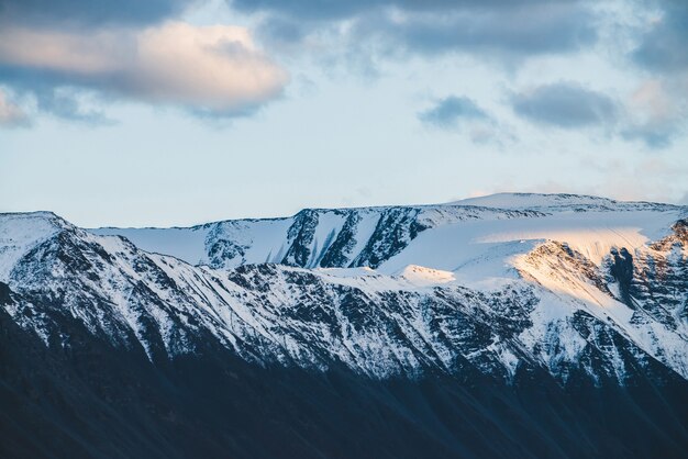 Atmosphärische alpine Landschaft zum schneebedeckten Bergrücken im Sonnenuntergang.