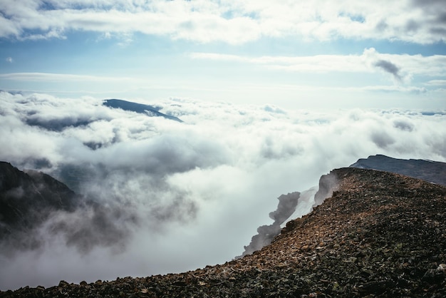 Atmosphärische Landschaft auf dem Bergrücken über den Wolken bis zum Scheitelpunkt in dicken niedrigen Wolken. Minimalistischer Blick vom Abgrund über Wolken. Schöne Landschaft mit Gebirgszug über dichten Wolken.