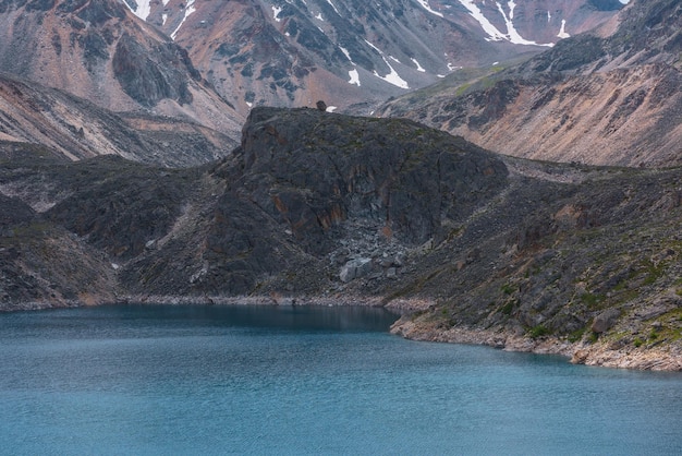 Atmosphärische Landschaft mit Wellen auf der Wasseroberfläche des tiefen Bergsees von phantomblauer Farbe zwischen scharfen Felsen und hohen Bergen Wunderbare dramatische Aussicht auf den tiefblauen Bergsee und die felsige Klippe