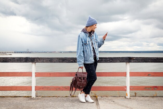 Atmosphärisches Lifestyle-Foto im Freien der jungen schönen dunkelhaarigen Frau in Strickmütze