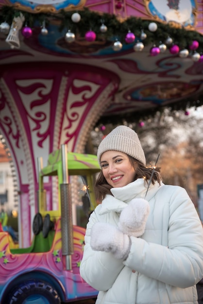 Atrações justas garota do carrossel vestida com uma jaqueta branca e um chapéu branco a garota sorri a garota se alegra com as emoções comemorando o natal ao ar livre