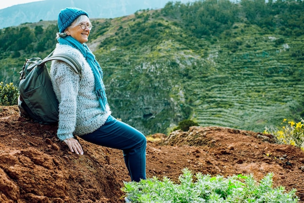 Atractiva anciana activa con mochila caminando por la montaña Sonriente anciana descansando admirando el paisaje desde la cima de la isla de Gomera