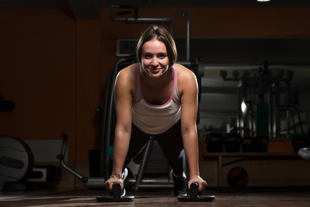 Atractiva atleta femenina realizando flexiones en el piso