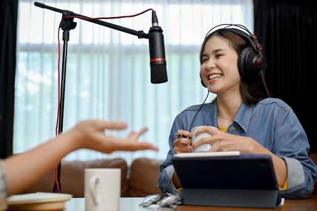 Atractiva bloguera asiática entrevistando a una invitada en un programa de podcast