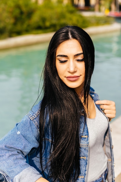 Atractiva chica de pelo negro con estilo disfruta del sol, sus ojos están cerrados, viaja por Azerbaiyán