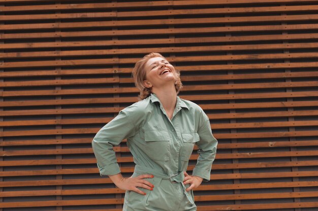 Atractiva chica sonriente de pie sobre fondo de pared de madera