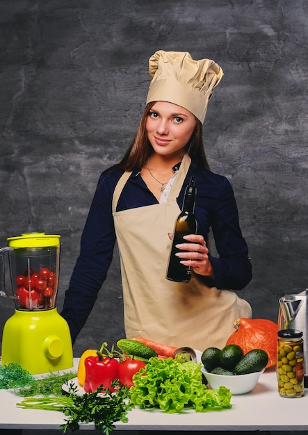 Atractiva cocinera cocinera sostiene una botella con aceite.