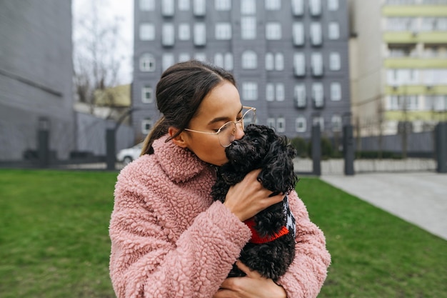 Atractiva dama besando caniche de juguete de raza de perro en un paseo Amor y mascotas