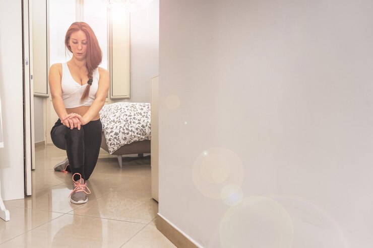 Foto atractiva desportista ruiva a treinar na sua bela casa a fazer alongamentos