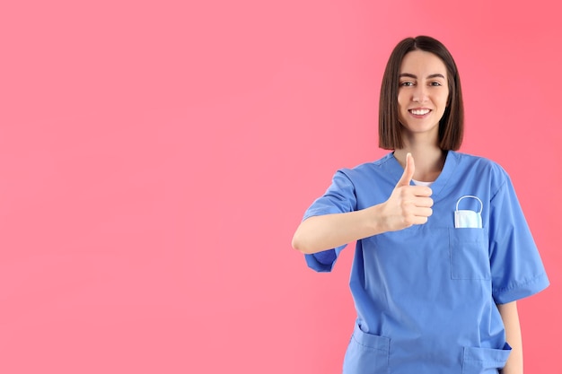 Atractiva enfermera en prácticas sobre fondo rosa