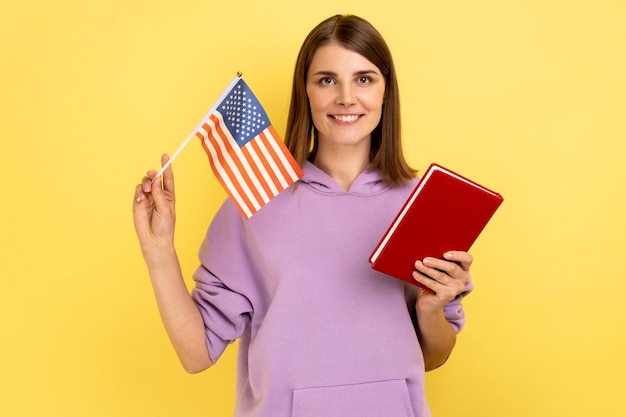 Atractiva estudiante de cabello oscuro tiene educación de libros y bandera americana en el extranjero en Estados Unidos