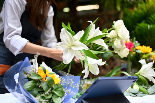 Atractiva florista asiática arreglando flores haciendo un ramo para ella en el cliente