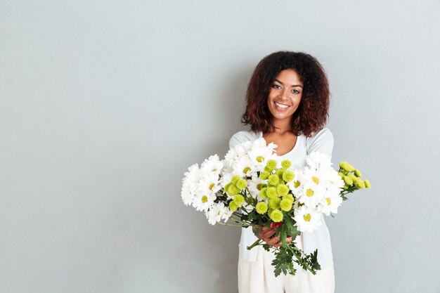 Atractiva joven africana dando ramo de flores a camrera