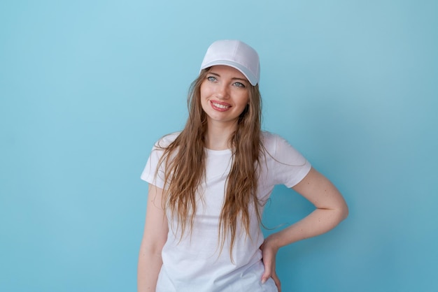 Atractiva joven amigable sonriendo felizmente usando una camiseta blanca y una gorra