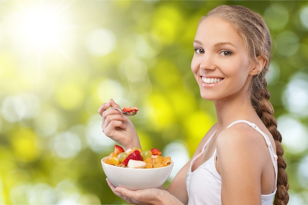 Atractiva joven disfrutando de frutas en el desayuno