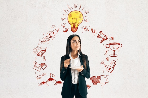 Atractiva joven empresaria europea bebiendo café y de pie sobre un fondo de pared de hormigón con una lámpara redonda de esbozo de negocios Idea y concepto de red