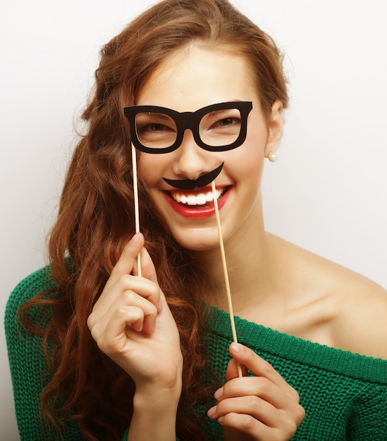 Atractiva joven juguetona con bigote y gafas en un palo.