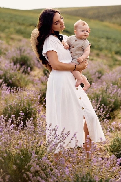 Atractiva joven madre jugando con su bebé en un campo de lavanda