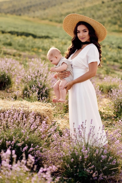 Atractiva joven madre jugando con su bebé en un campo de lavanda