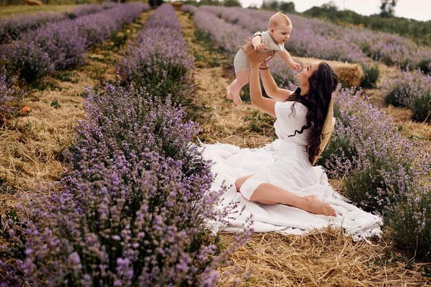 Atractiva joven madre jugando con su bebé en un campo de lavanda