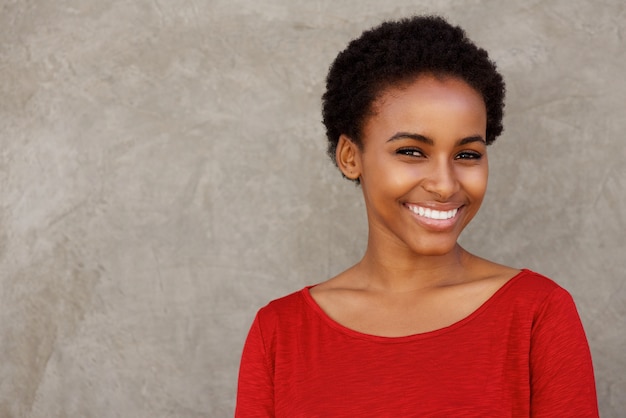 Atractiva joven mujer negra en camisa roja sonriendo