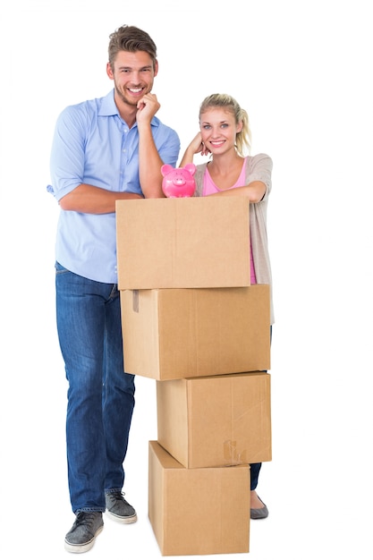 Atractiva joven pareja apoyándose en cajas con hucha